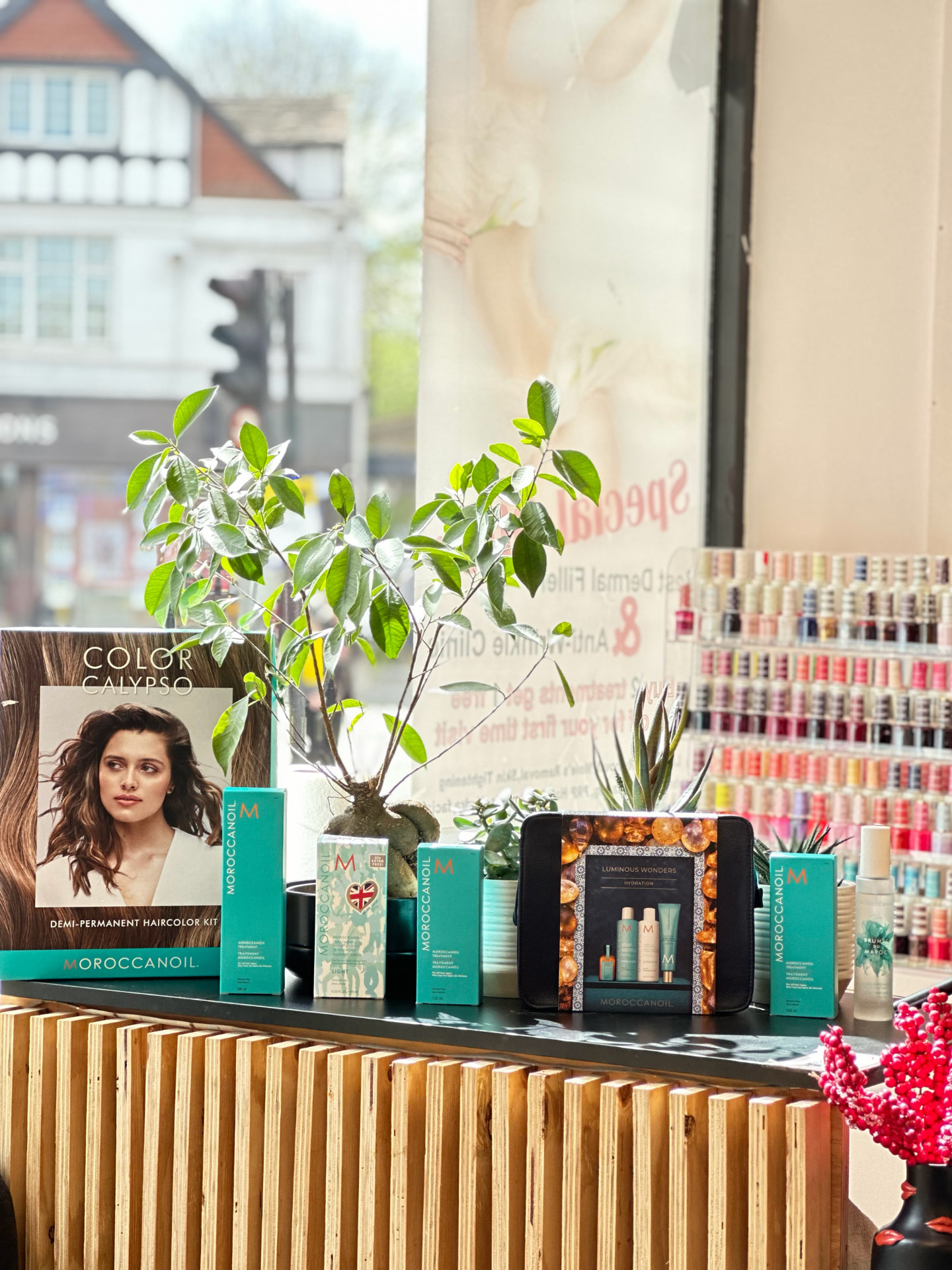 Moroccanoil haircare display on a slatted timber counter with a wall of nail polish colours behind it.