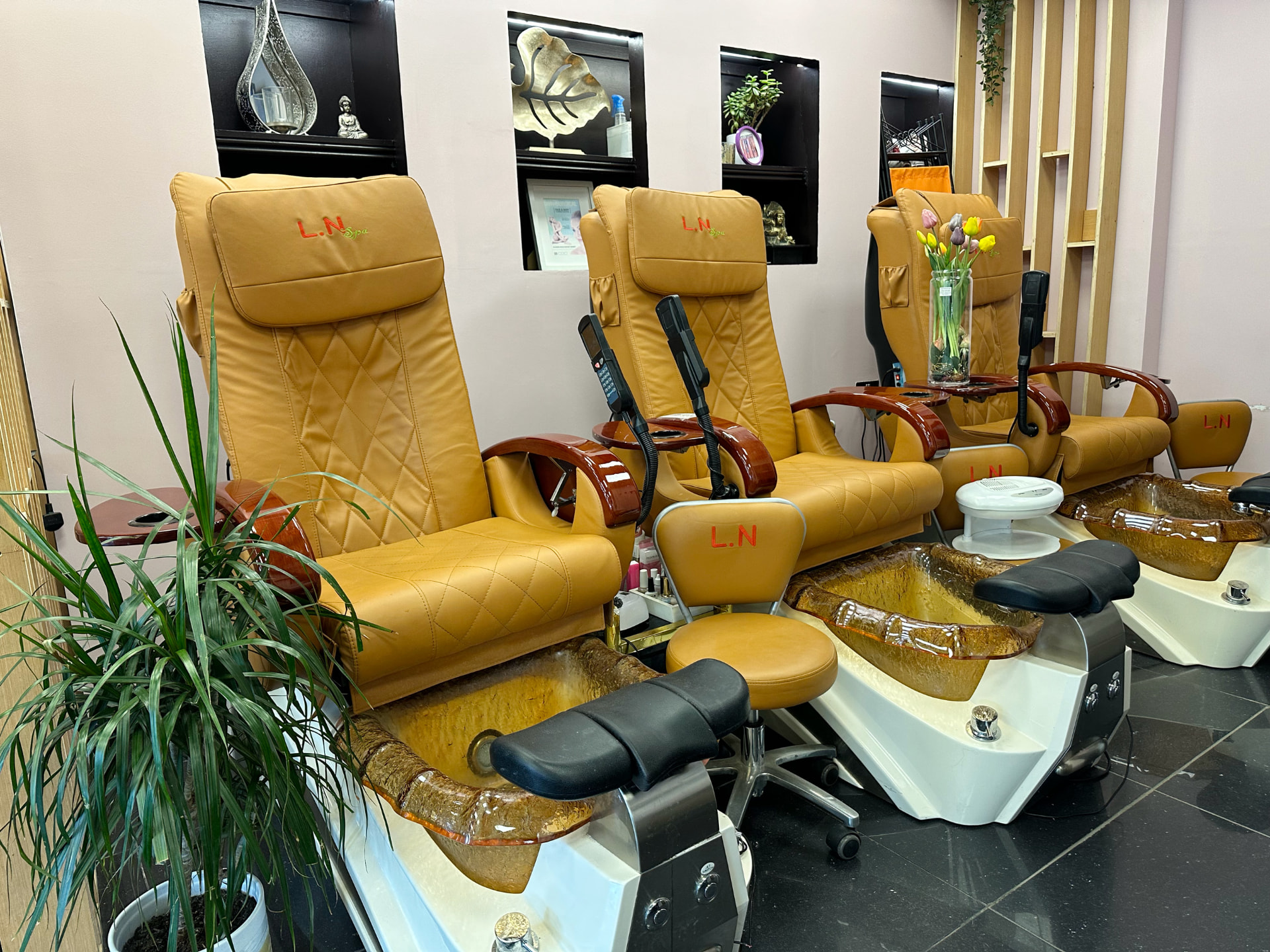 Close view of the tan leather pedicure spa chairs and glass foot basins.